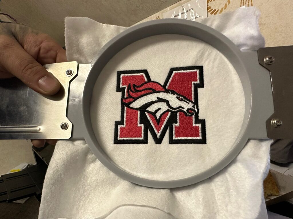 Red and black embroidered logo for a local school jacket / uniform