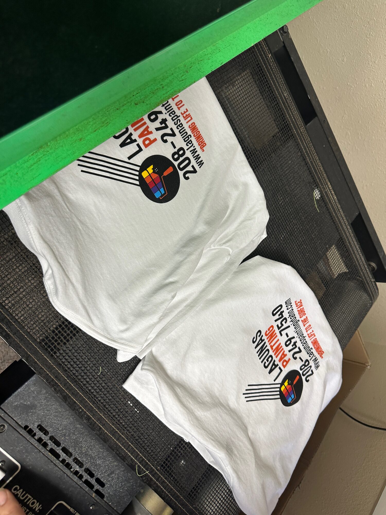 Multi color screen printed t-shirts being loaded onto a dryer