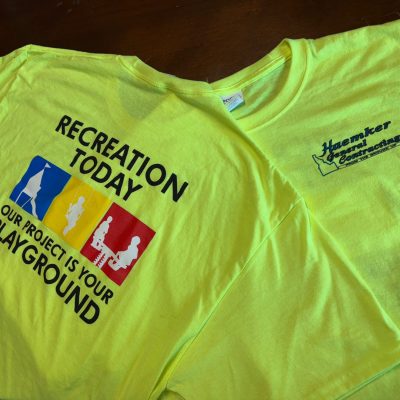 Custom screen printed shirts with front and back placement on safety green shirts for a construction company near Nampa