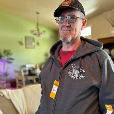 Army vet showing off their embroidered hoodie with custom Navy design embroidered onto chest and back