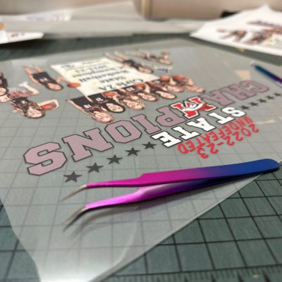 Custom HTV print with weeding tool ready for application onto a custom vinyl shirt