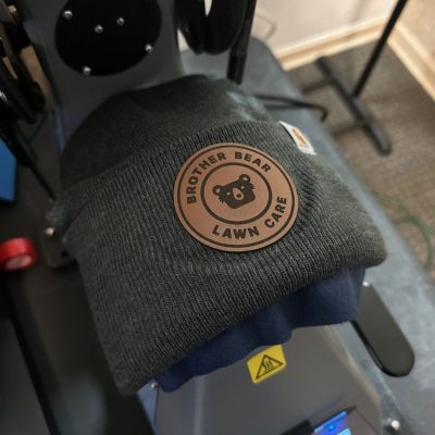 Custom leather patch being applied to a beanie at The Print Plug