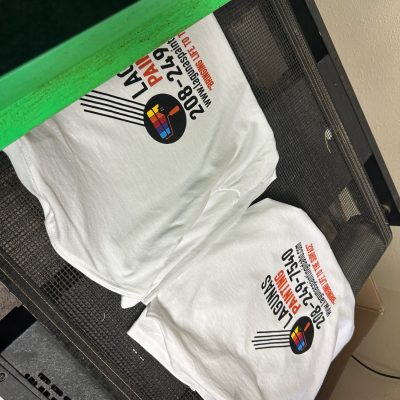 Multi color screen printed t-shirts being loaded onto a dryer